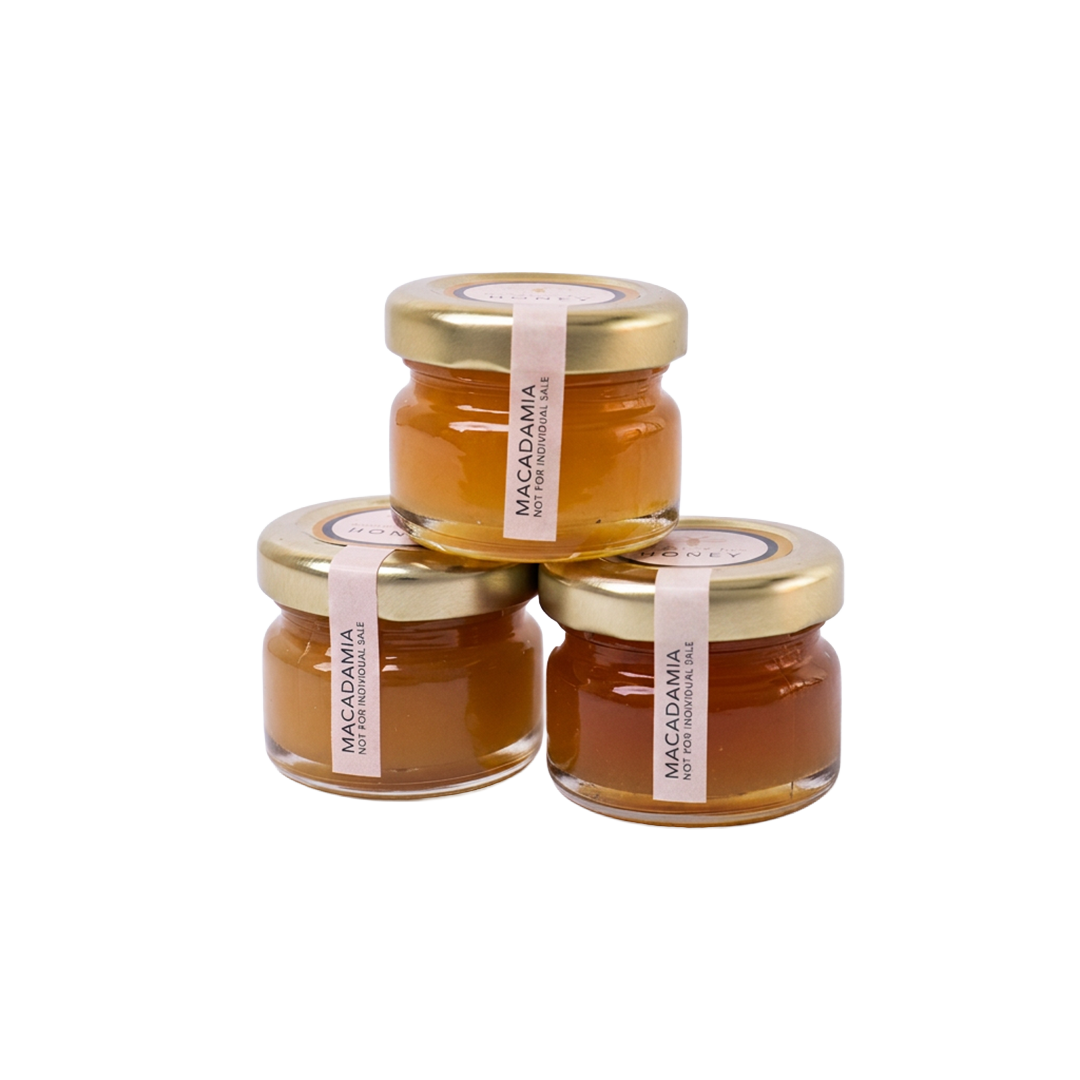 Three small glass jars of Meant To Bee Macadamia honey stacked together.